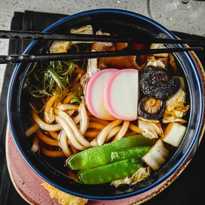 Close-up of a bowl of Japanese udon noodles with chopsticks.