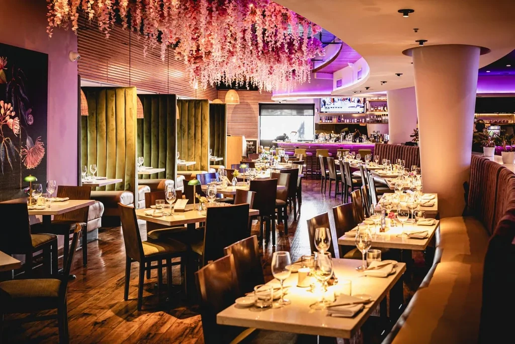 Restaurant dining area with flower-adorned ceiling and olive-green booths.