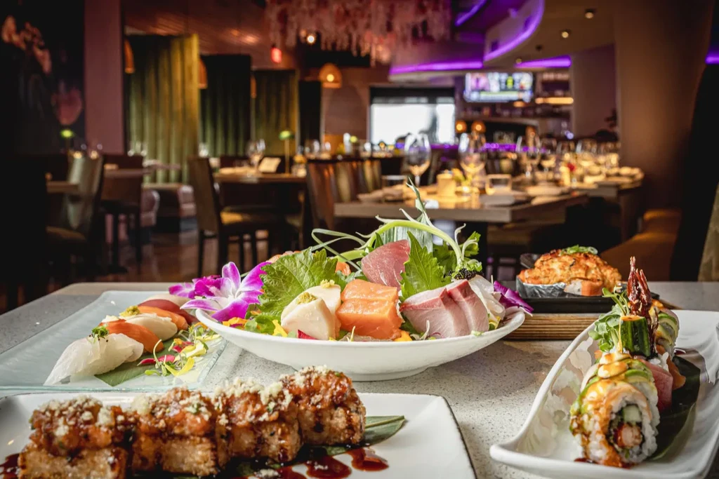 Assortment of sushi and sashimi platters on white serving dishes.