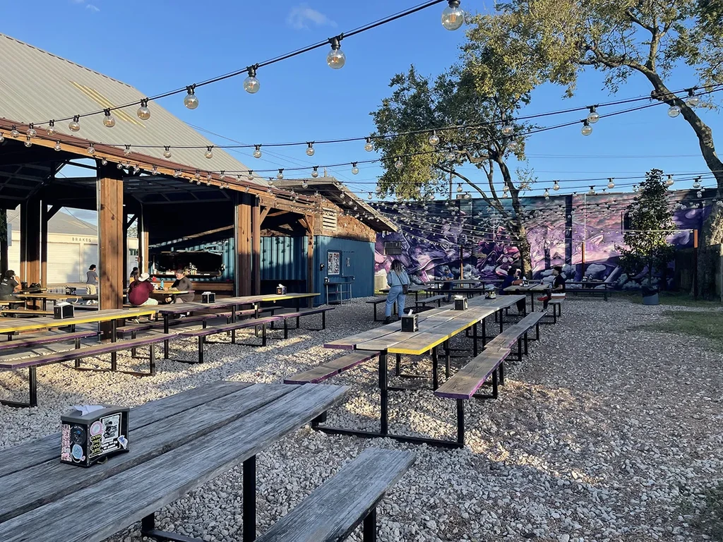 Outdoor casual dining area with picnic tables and globe lights.