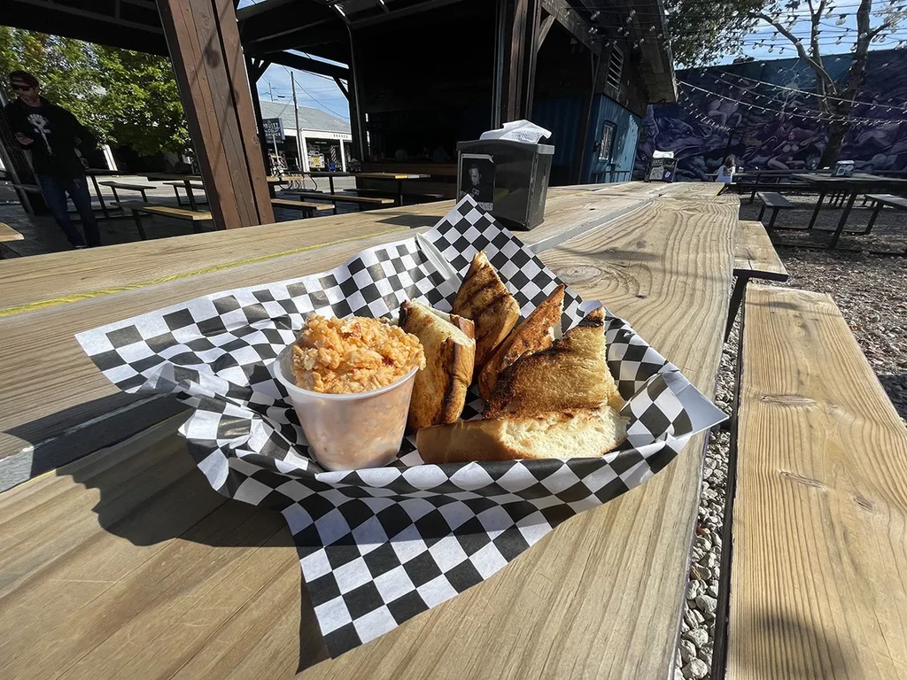 Toasted bread and orange dip on a wooden picnic table.