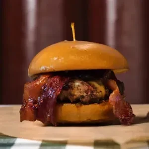 Gourmet burger with brioche bun, beef patty, melted cheese, and bacon.