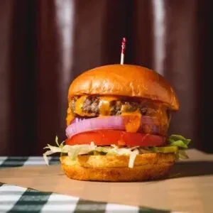 Double cheeseburger with melted cheese, red onion, tomato, and lettuce.