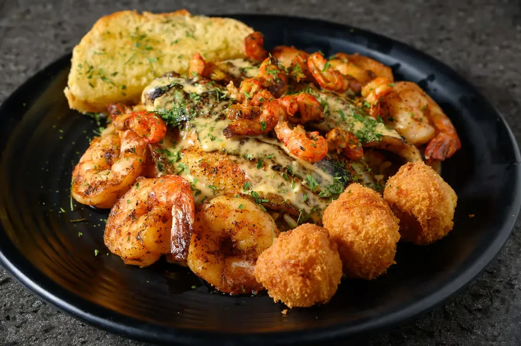 Seafood platter with fish, prawns, crawfish, garlic bread, and hushpuppies.