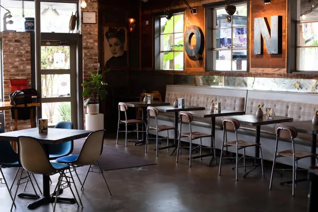 Daylit interior of a cafe with tables, chairs, and booth seating.