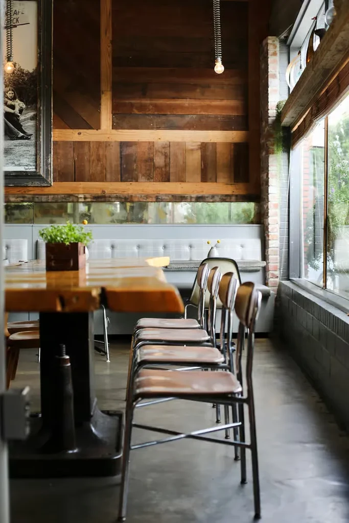 Rustic communal table with chairs and booth seating in a restaurant.