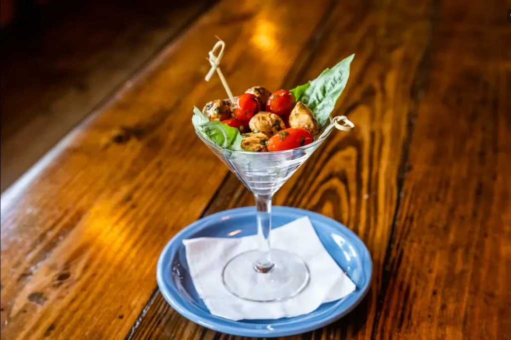 Martini glass filled with caprese skewers on a wooden table.