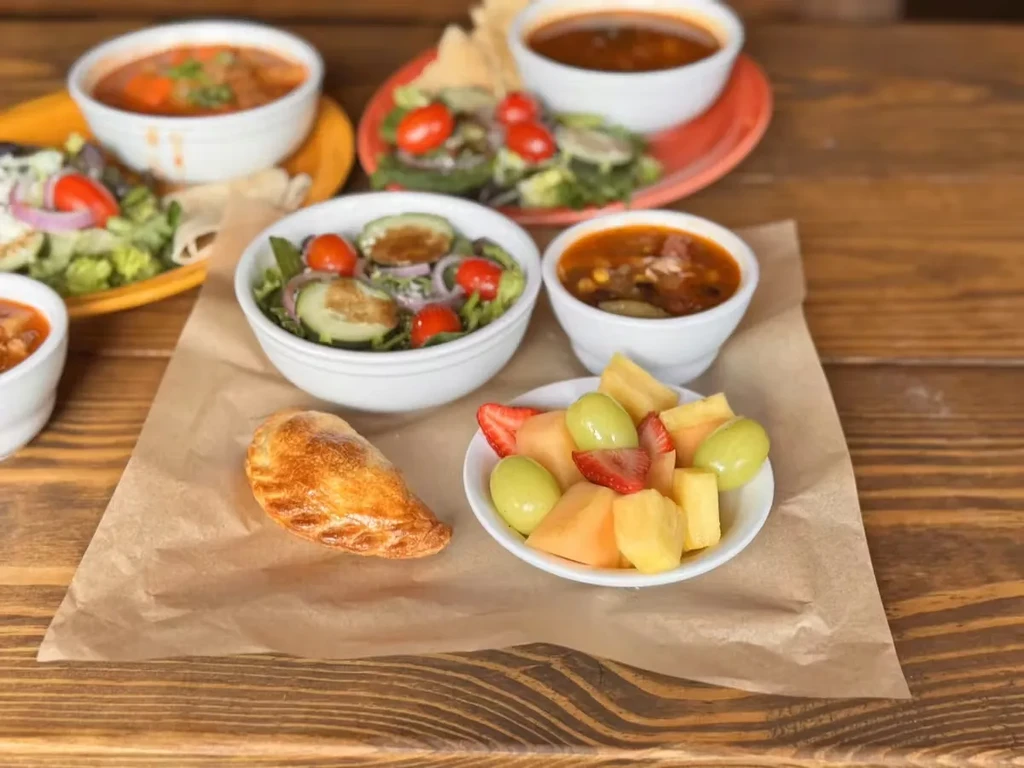 Variety of food items, including fruit salad, pastry, and stews.