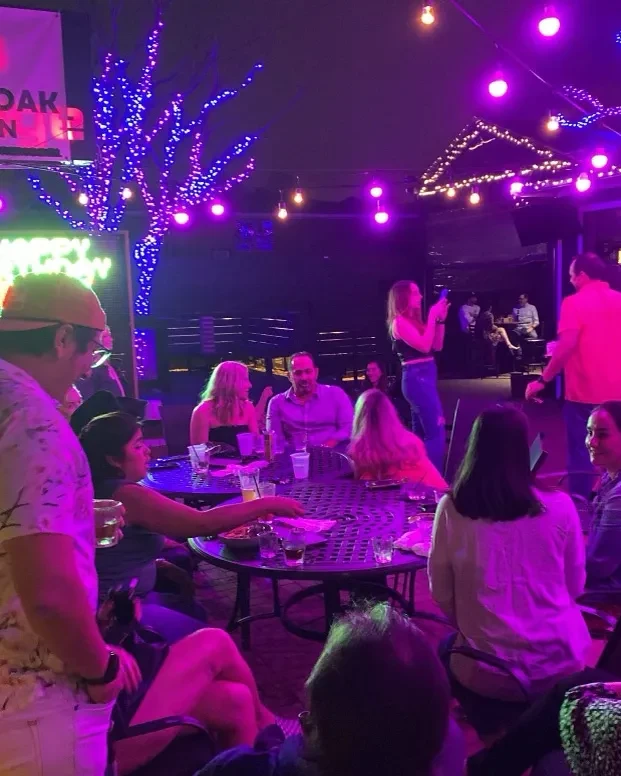 Outdoor restaurant patio at night with purple lights and people.