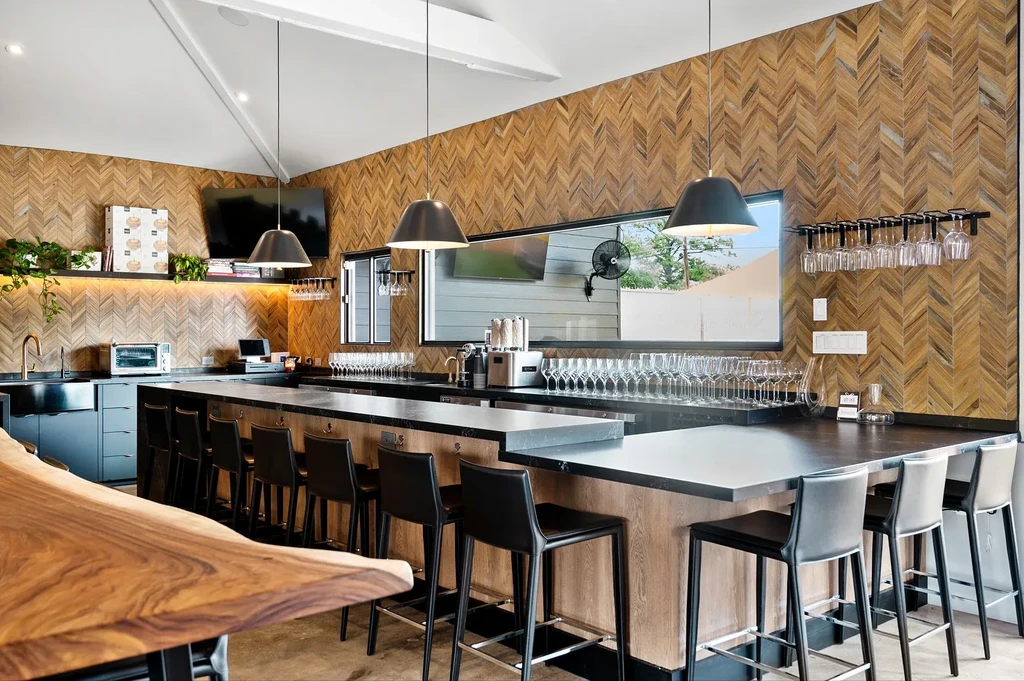 Interior of a modern bar with a long counter and wood paneling.