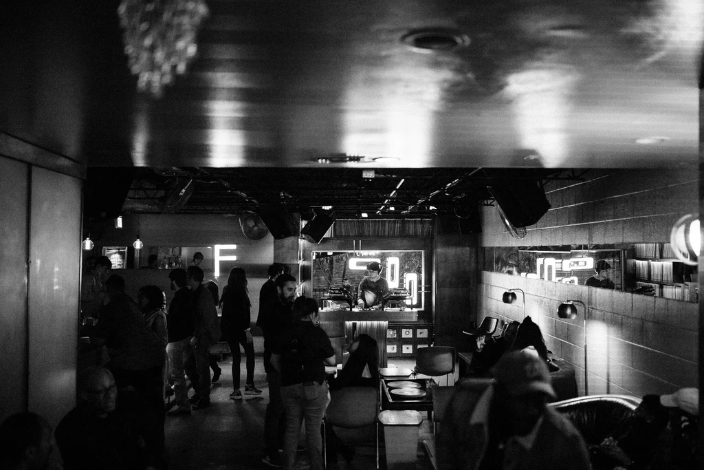 Black and white photo of a DJ mixing music in a dark club.
