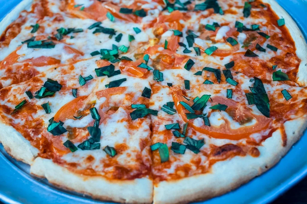 Close-up of a freshly baked pizza with tomatoes, mozzarella, and basil.