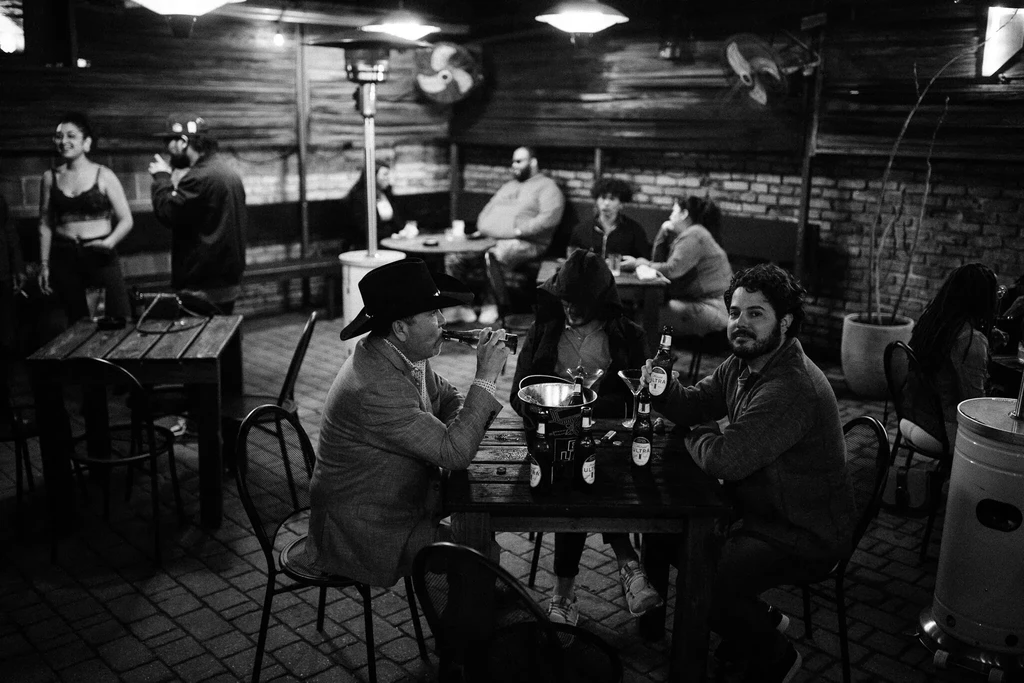 People drinking beer and socializing in a lively indoor restaurant.