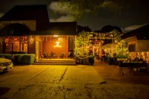 Restaurant exterior at night with illuminated patio and string lights.