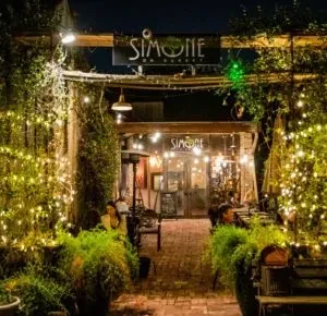 SIMONE on Sunset restaurant entrance with brick path, plants, and string lights.