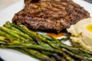 Steak, asparagus, and mashed potatoes on a white plate.