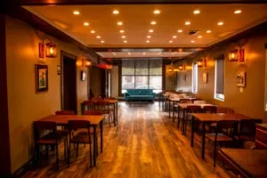 Empty restaurant interior with wooden tables, chairs, and warm lighting.