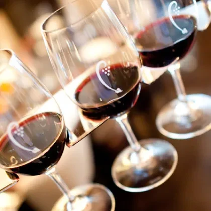 Three etched wine glasses, partially filled with red wine.