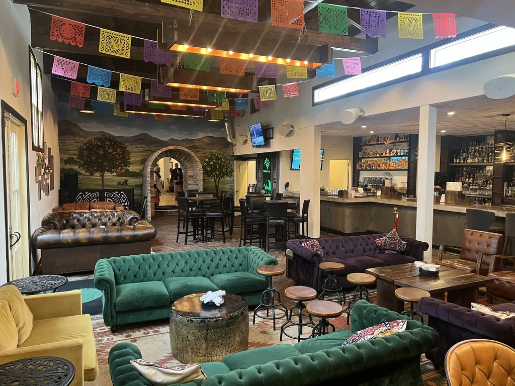 Restaurant interior with colorful sofas, a bar, and a mural.