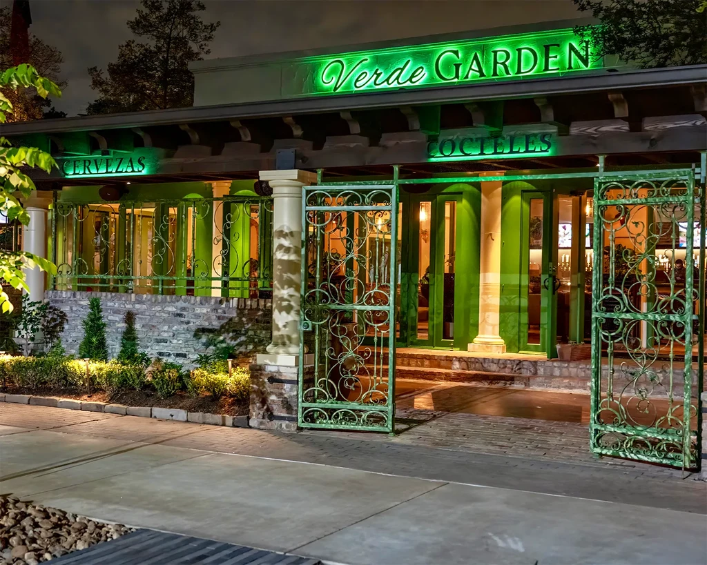 Exterior of Verde Garden restaurant with green neon signs at night.