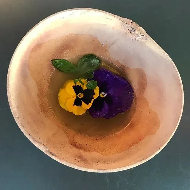 Overhead shot of two pansies and leaves floating in a bowl.