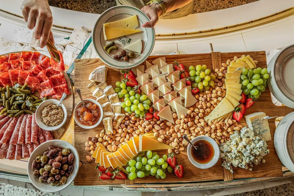 Overhead view of a person serving a charcuterie and cheese board.