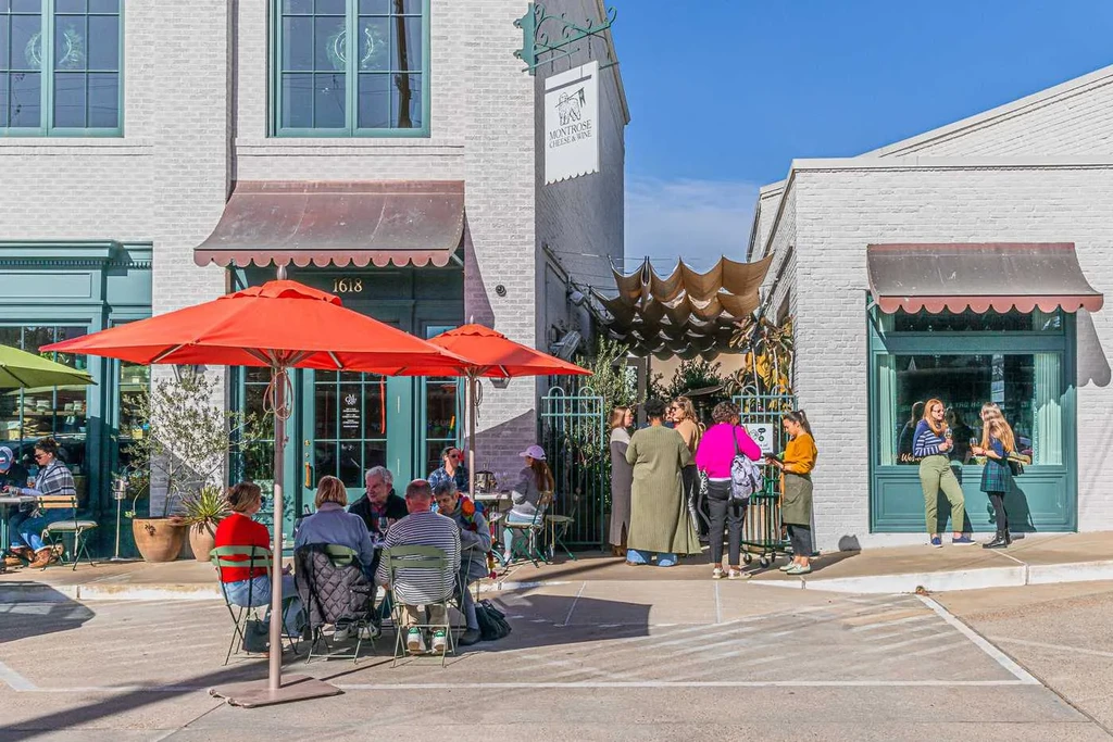Restaurant exterior with teal frames, red umbrellas, and patrons.