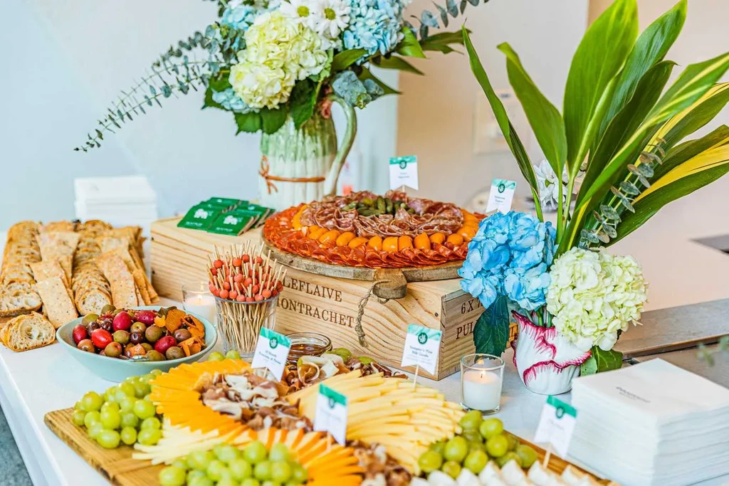 Lavish buffet with charcuterie, olives, breads, and floral arrangements.