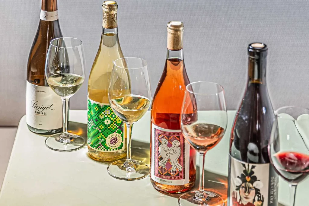 Five wine bottles and glasses, white, rosé, and red wines.