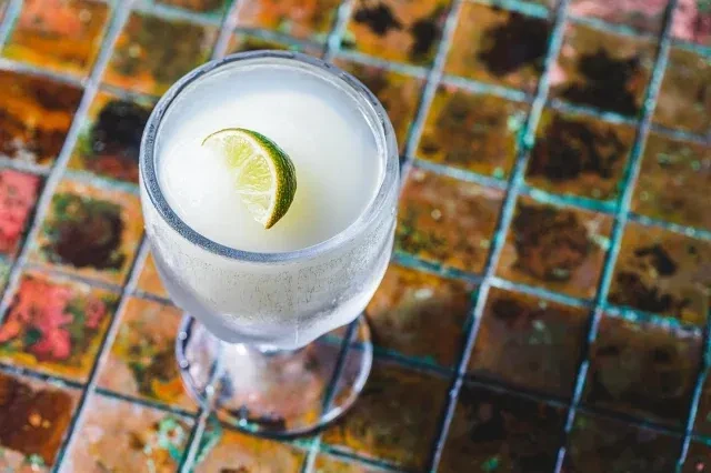 Close-up overhead shot of a frosty white cocktail with a lime.