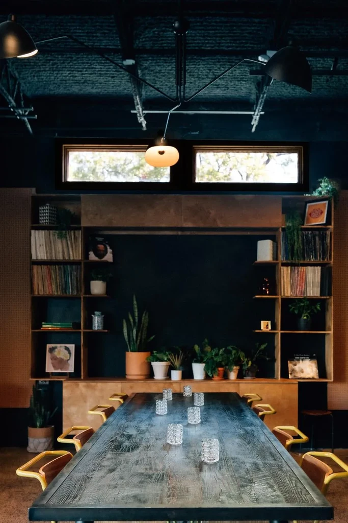 Stylish interior with a long wooden communal table and shelves.