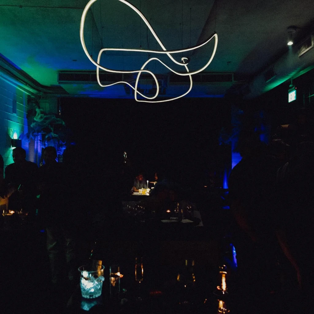 Dimly lit restaurant interior with modern neon light fixture.