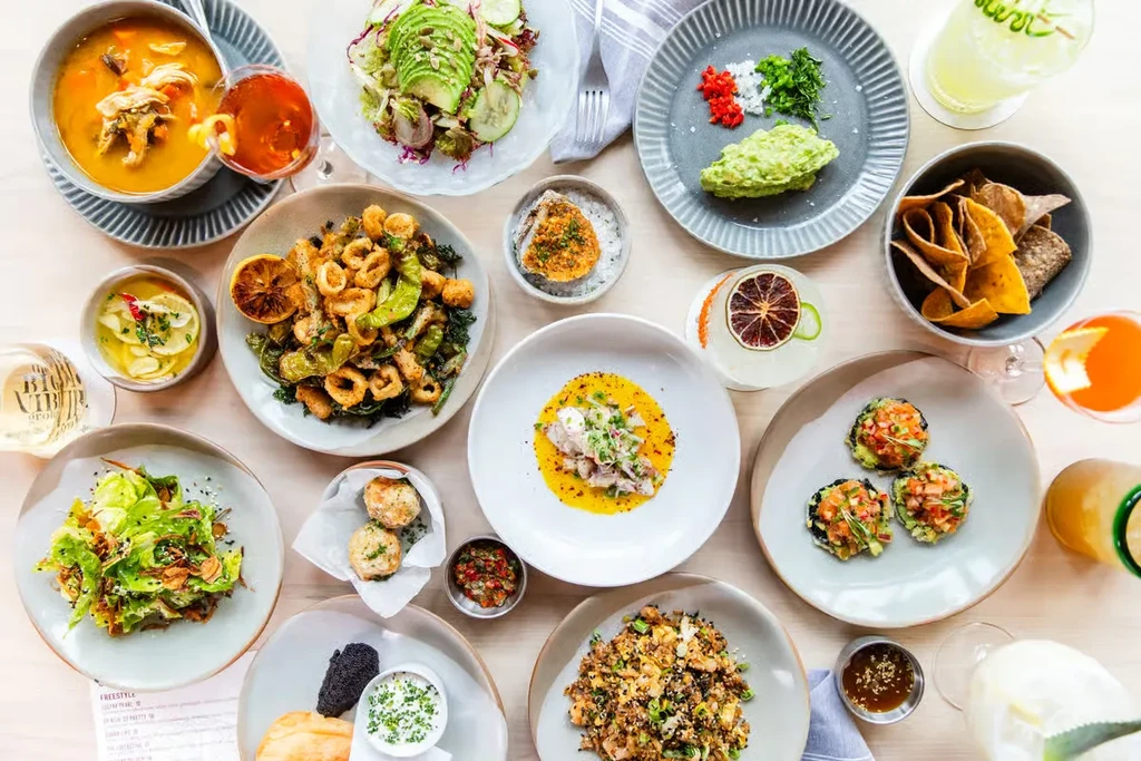 Overhead view of a wooden table laden with diverse dishes and drinks.