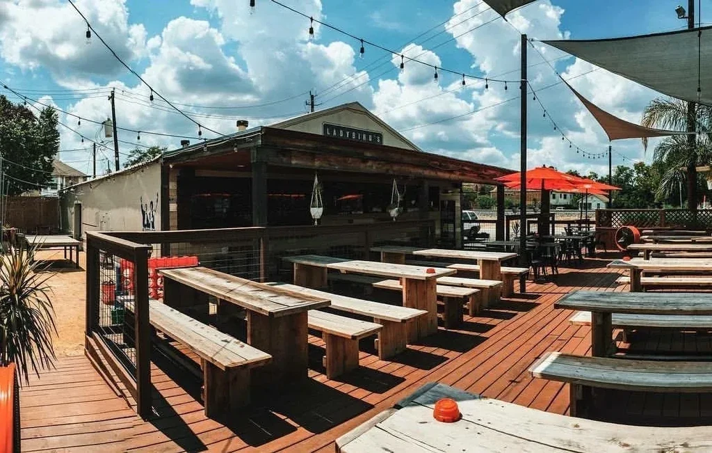 Ladybird's outdoor patio with picnic tables, shade sails, and string lights.