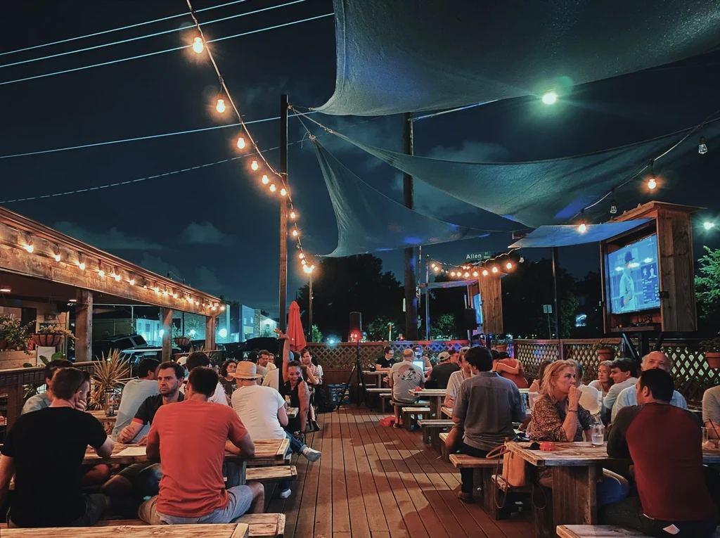 Nighttime patio of an urban restaurant with string lights and customers.