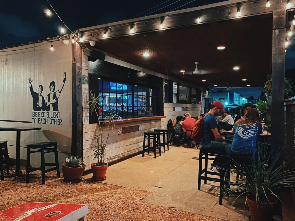 Outdoor restaurant patio at night with string lights and patrons.