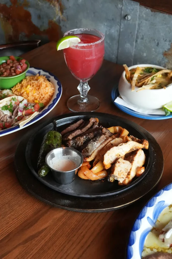 Mexican-style food on a wooden table with a rustic metal wall.