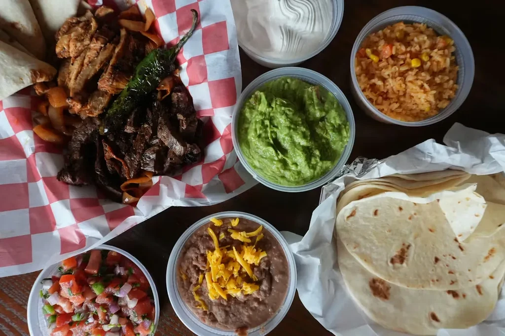 Fajita platter with sides of guacamole, beans, rice, and pico de gallo.