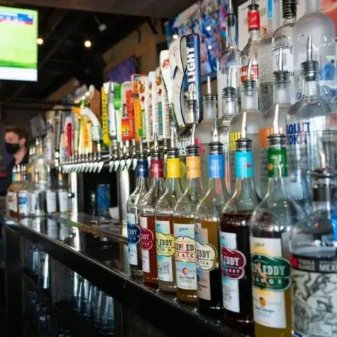Well-stocked bar with beer taps and “TIRED TEDDY” liquor bottles.