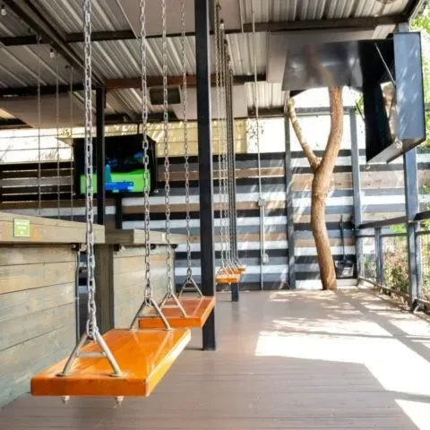 Restaurant bar with wooden swing seats in front of a counter.