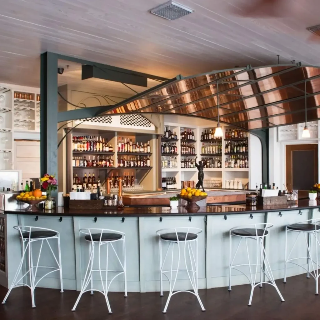 Well-lit, upscale bar area with liquor display and bar stools.