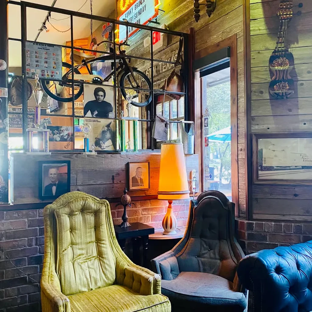 Vintage restaurant interior with eclectic decor, armchairs, brick wall, and bicycle.