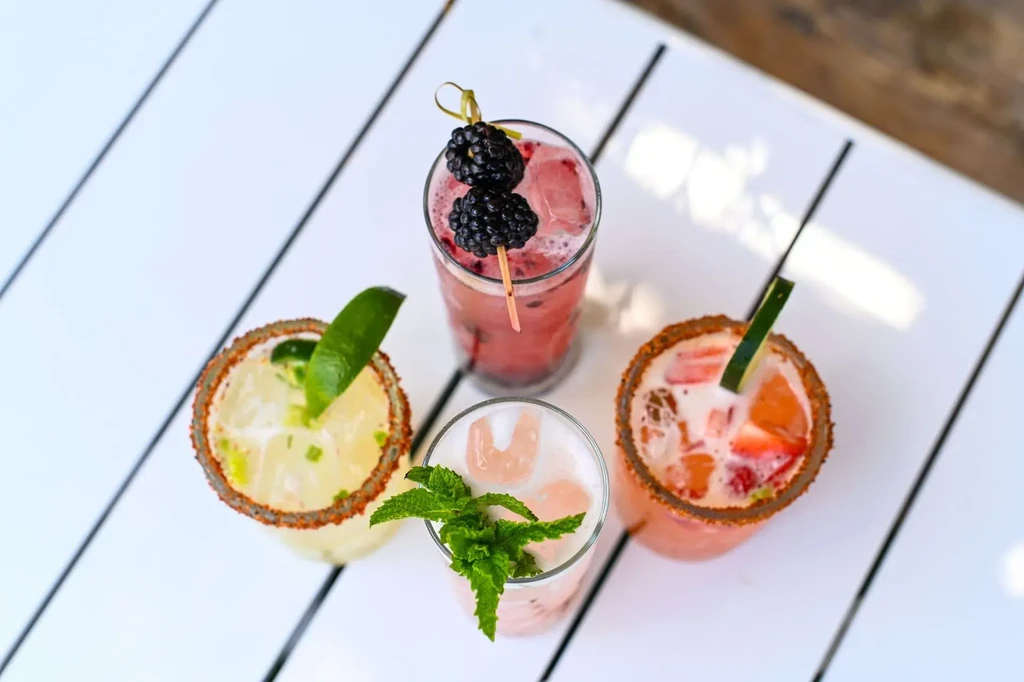 Four colorful cocktails, each in a unique glass with garnishes.