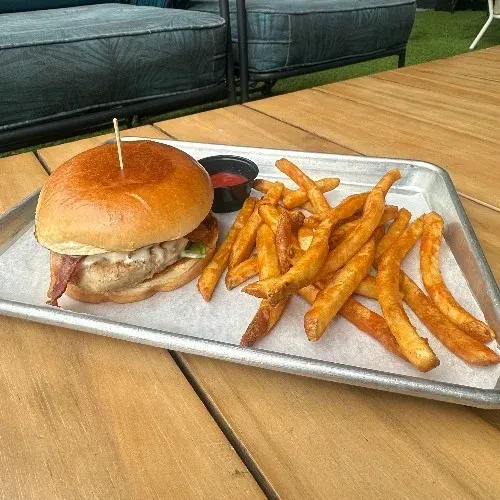 A burger, fries, and ketchup served on a metal tray.