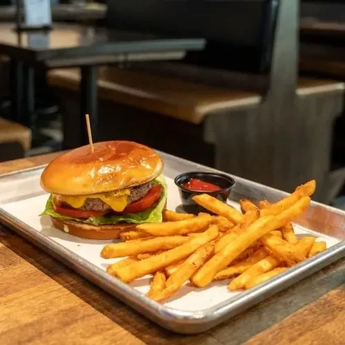 Cheeseburger and french fries on a metal tray with ketchup.