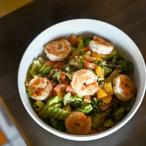 Overhead view of grilled shrimp salad with lettuce and tomatoes.