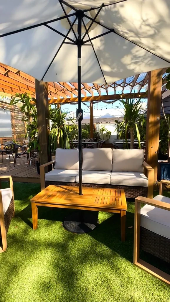 Outdoor restaurant patio with tables, chairs, umbrella, and artificial turf.