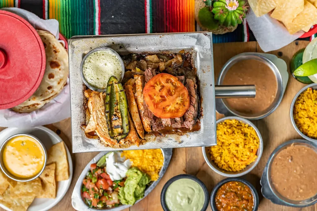 Overhead view of a Mexican fajita meal on a wooden table.