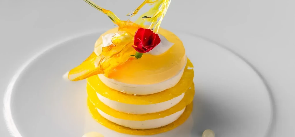 Elegant, layered lemon dessert with caramel wings and a red flower.