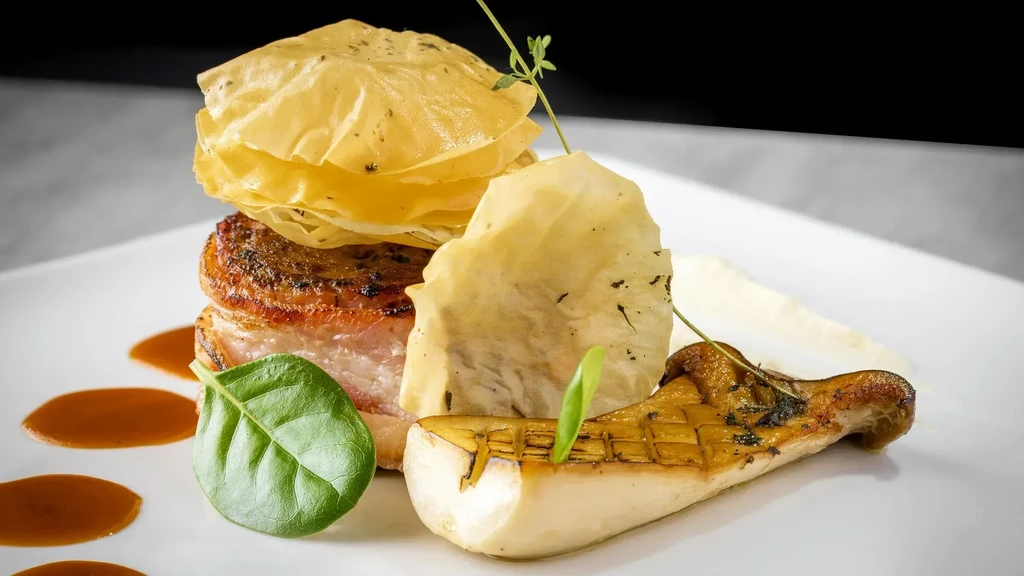 Seared meat, crispy pastry, grilled mushroom, and sauce on a white plate.